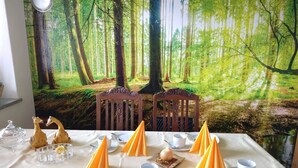 A dining table set with plates, cutlery, and napkins, with a forest-themed backdrop. - Holiday flat ‘Grabmeier - Number 2’ with mountain view, balcony and Wi-Fi (Grainet)