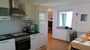 A modern kitchen with a stove, oven, and coffee maker. - Holiday flat ‘Grabmeier - Number 2’ with mountain view, balcony and Wi-Fi (Grainet)
