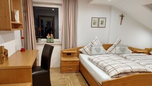A bedroom with a wooden bed, a desk, a chair, and a small bedside table. - Holiday flat ‘Grabmeier - Number 2  ’ with mountain view, balcony and Wi-Fi (Grainet)