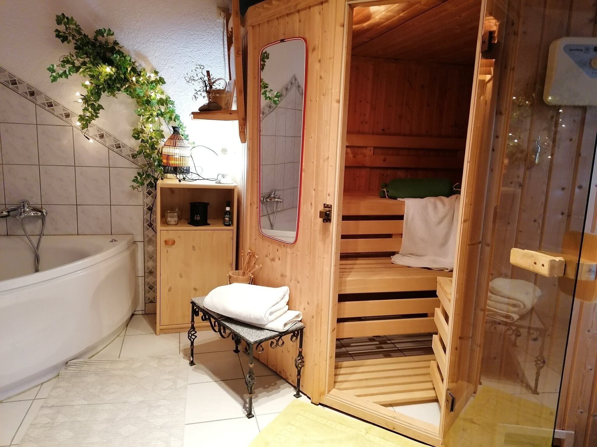 En træsauna med bænk, et træskab med toiletartikler og et badekar.