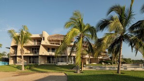 A resort with a modern architectural style, featuring a central building with multiple balconies and a thatched roof structure.