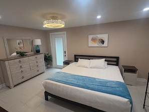 A bedroom with a bed, dresser, bedside tables, a mirror, a potted plant, and a ceiling light fixture. - Charming 3-bedroom house with pool, AC, WiFi in pleasant Tampa (Tampa)