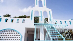 A white building with a blue staircase and arched windows. - Xing Ocean Homestay VT by Bay Luxury (Ho Chi Minh City)