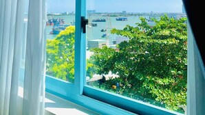 A window with a view of a harbor, boats, and greenery. - Xing Ocean Homestay VT by Bay Luxury (Ho Chi Minh City)