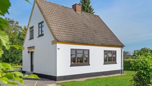 A small, single-story house with a sloped roof, white exterior walls, and a small front porch. - Lovely home in Dronninglund with WiFi (Dronninglund)