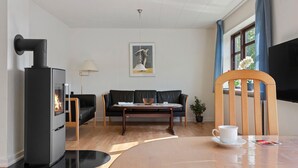 A modern living room with a fireplace, a sofa, a dining table with a cup and saucer, and a television. - Lovely home in Dronninglund with WiFi (Dronninglund)