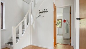 A staircase with white railings leading to a room with a wooden floor. A coat rack and a towel hanging on a door are visible. - Lovely home in Dronninglund with WiFi (Dronninglund)
