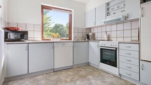 A modern kitchen with white cabinets, a microwave, a coffee maker, and a stove. - Lovely home in Dronninglund with WiFi (Dronninglund)