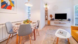 Una sala de estar moderna con comedor, televisor y sofá amarillo.