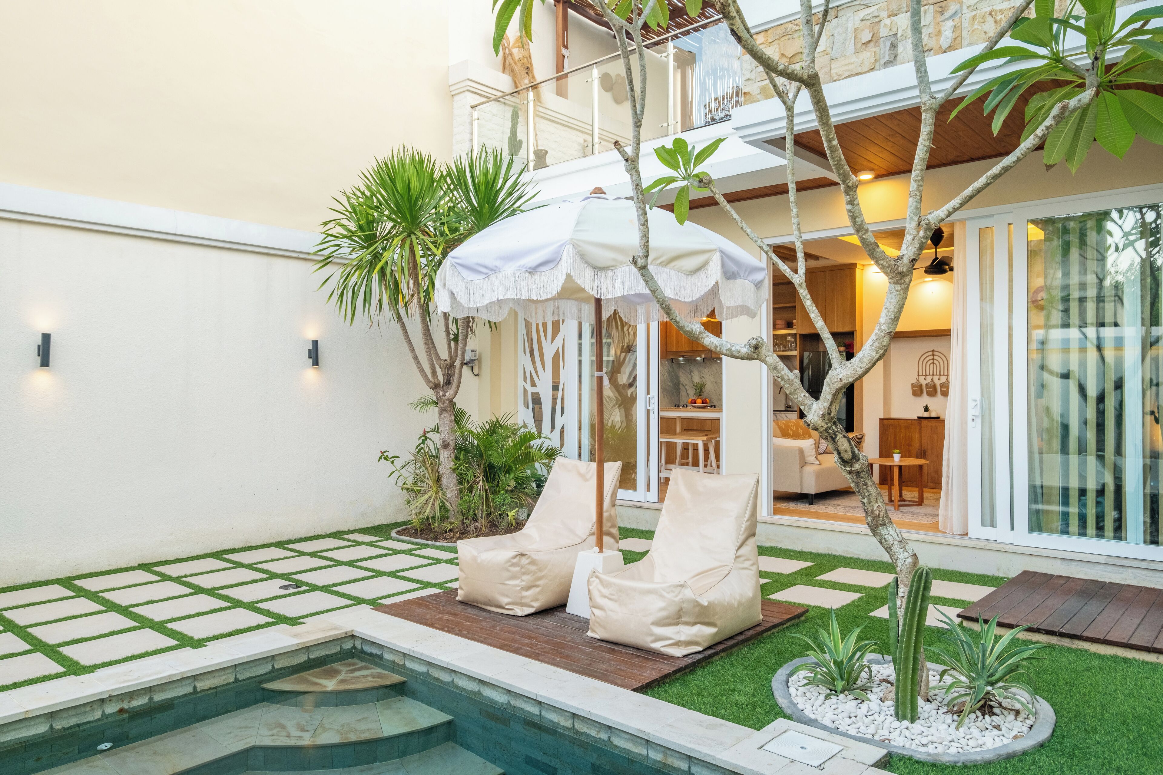 Un área de piscina con dos sillas reclinables, una piscina pequeña y una zona de estar cubierta con toldo.
