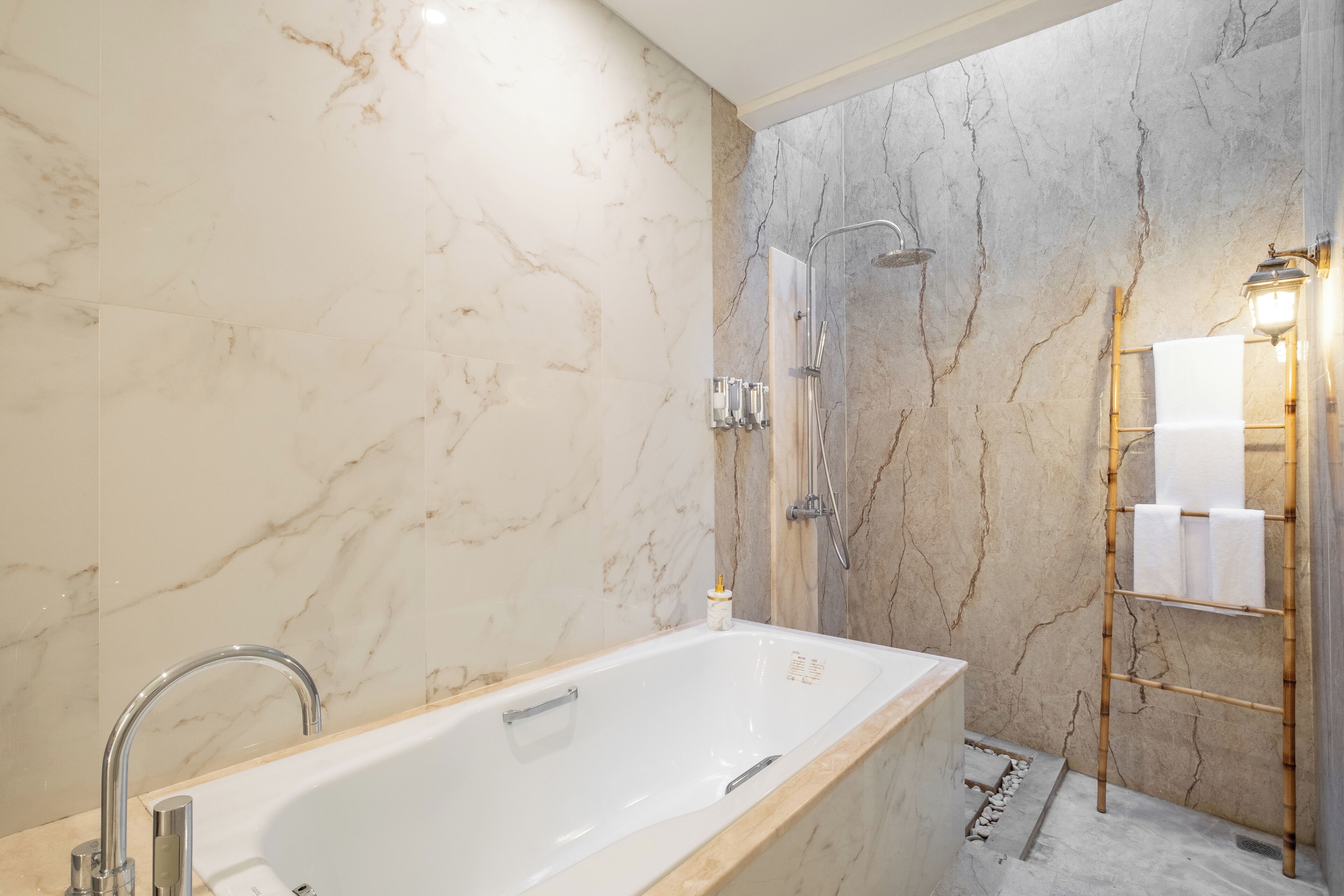 Un baño moderno con una bañera independiente, zona de ducha y un toallero de bambú.