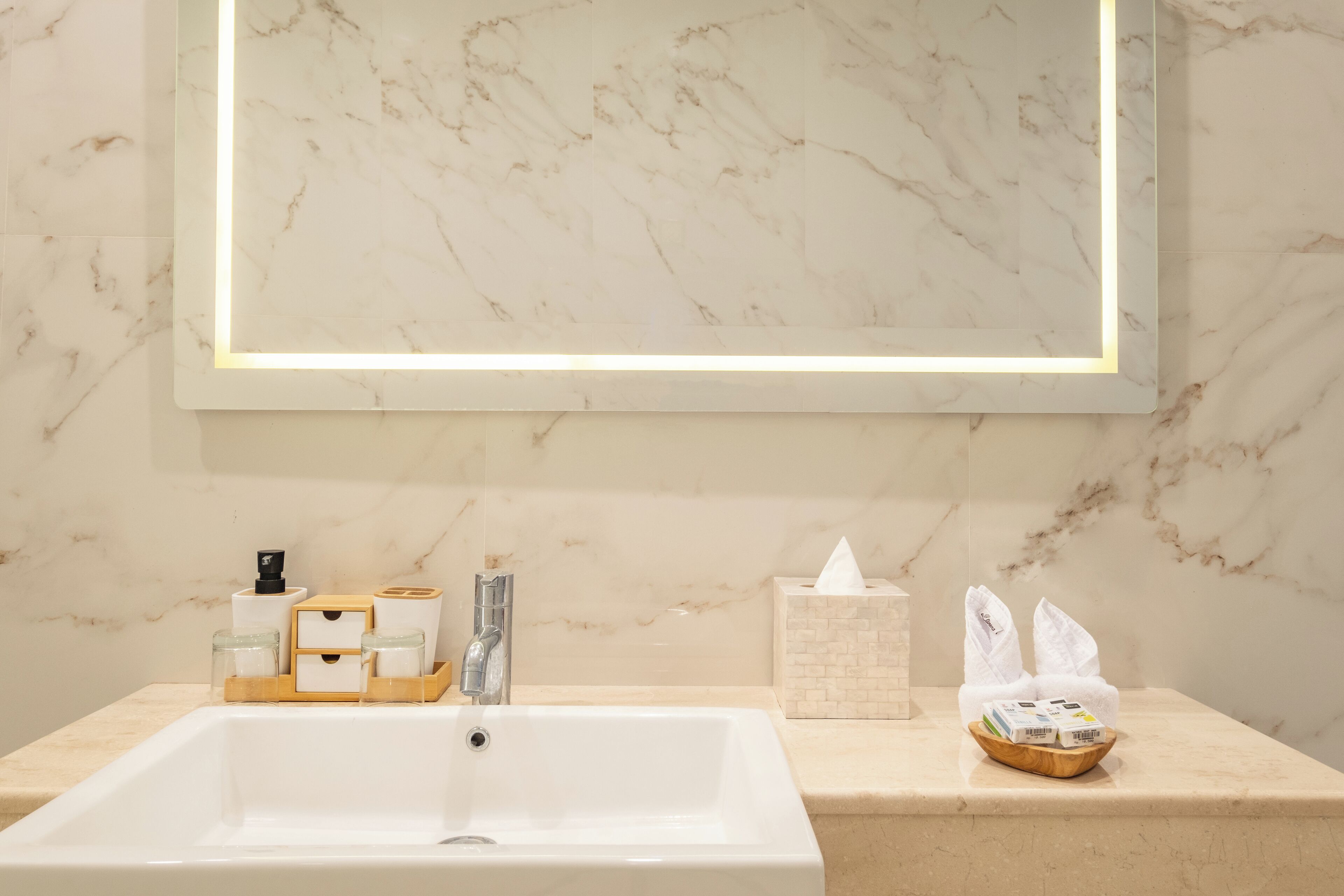 Un bagno con lavabo in marmo, uno specchio e articoli da toilette sul ripiano.