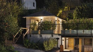 Ein modernes Haus mit einem Glasbalkon, einer Treppe zum Eingang und einem hellen Innenraum.