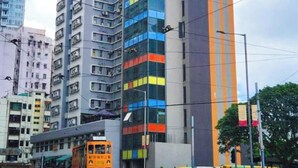 A high-rise building with multiple floors, a mix of glass and concrete facades, and a prominent orange stripe. - China Rich Oriental Hotel (Hong Kong)