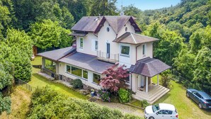 Ein zweistöckiges Haus mit einer großen Veranda, einer Garage und einem gepflegten Garten.