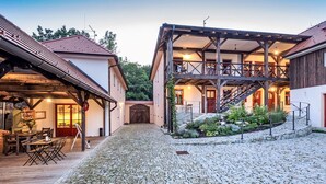 A rustic building with a stone courtyard, wooden deck, and a covered outdoor seating area.