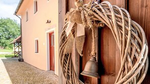 A rustic wooden door with a woven wreath and a bell hanging on it.