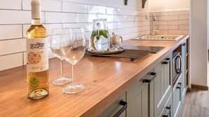 A kitchen with a wooden countertop, a wine bottle, and two glasses.
