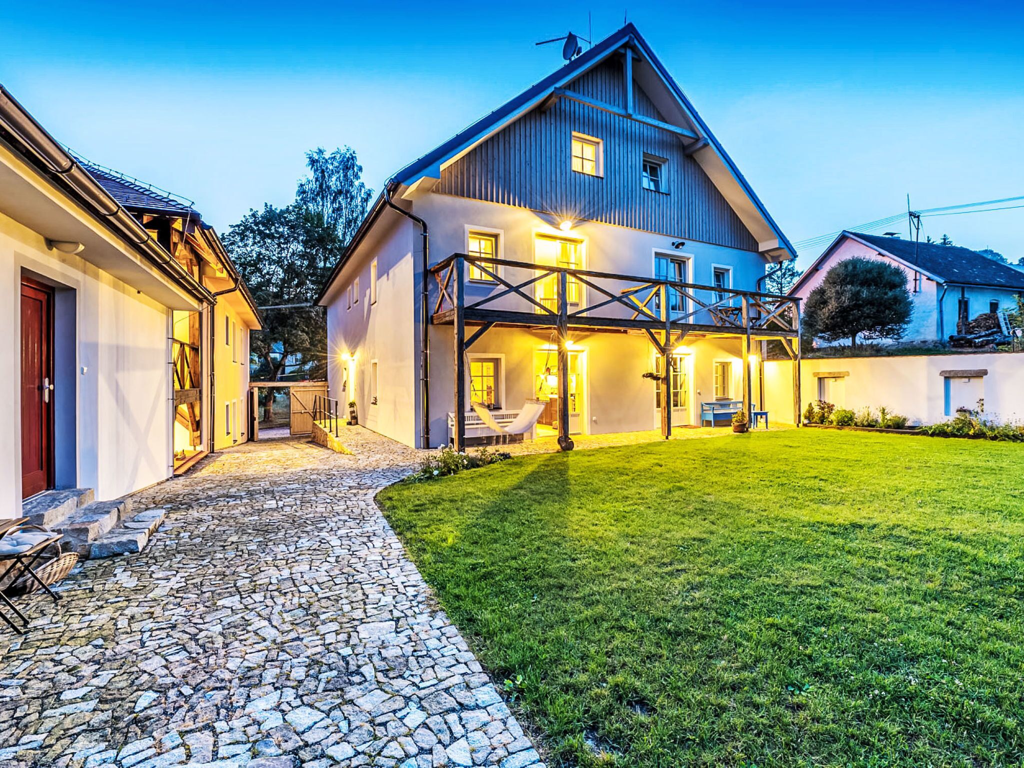 A two-story house with a stone pathway leading to a grassy yard.