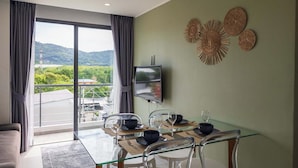 Un comedor moderno con una mesa de vidrio, sillas y un televisor montado en la pared.