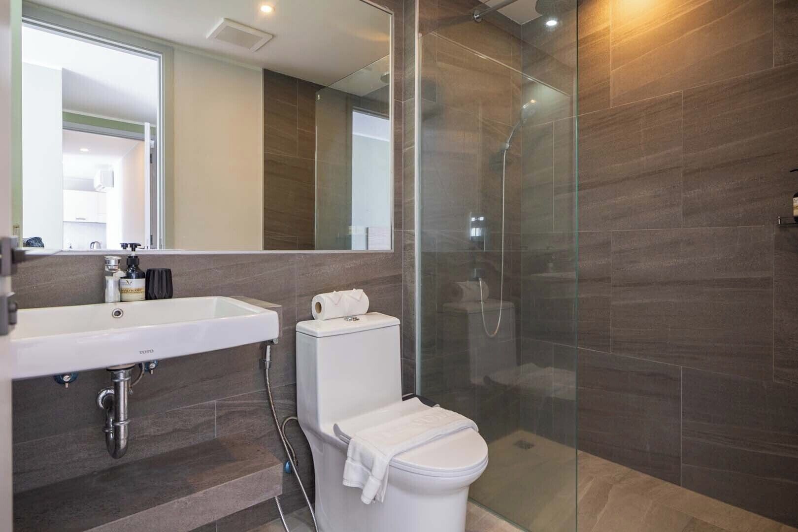 A modern bathroom with a glass shower enclosure, a white sink, and a toilet.