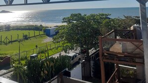 A view from a balcony overlooking a beach with a bridge in the background. - Beach House Delegado Marcio (Praia do Estaleiro Balneário Camboriú)