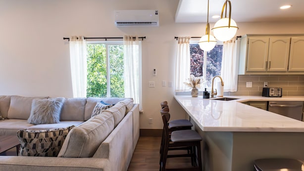 A modern kitchen with a built-in island, bar stools, and a large window with curtains. - Shasta Lake Beautiful House w/ Hot Tub, BBQ, Ping Pong & Foosball Table (Redding)