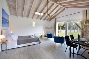 Ein modernes Schlafzimmer mit Bett, Nachttisch und einem Essbereich mit Stühlen und Tisch.