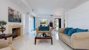 A spacious living room with a fireplace, two sofas, a coffee table, and a large painting on the wall. - Villa Noulia With 4 Bedrooms and 2 Bathrooms (Corfu)