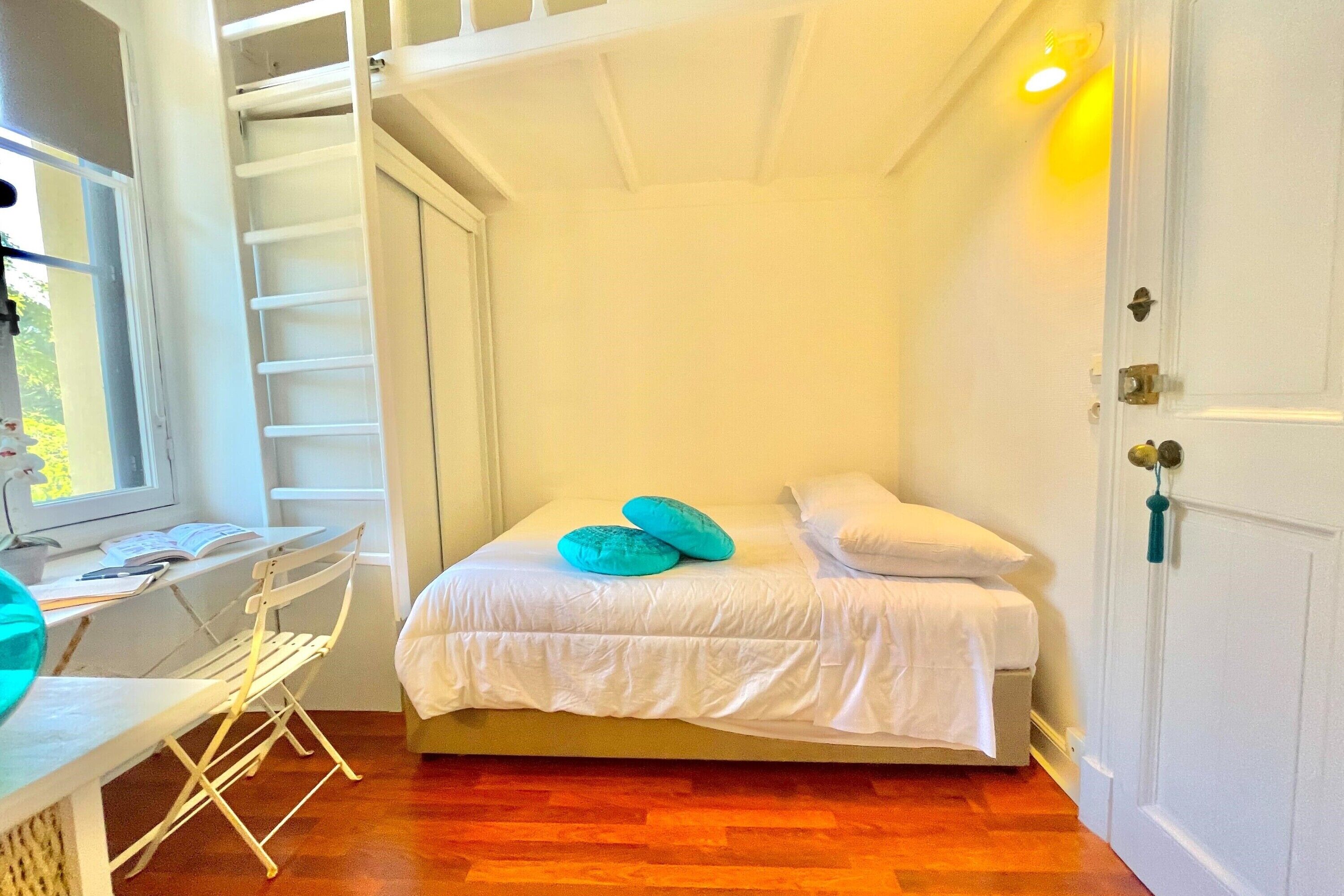 Un dormitorio con cama, escritorio y ventana.
