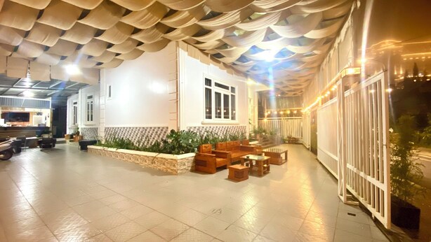 Un'ampia zona interna con pavimento piastrellato, un'area salotto con mobili in legno e un soffitto decorativo.