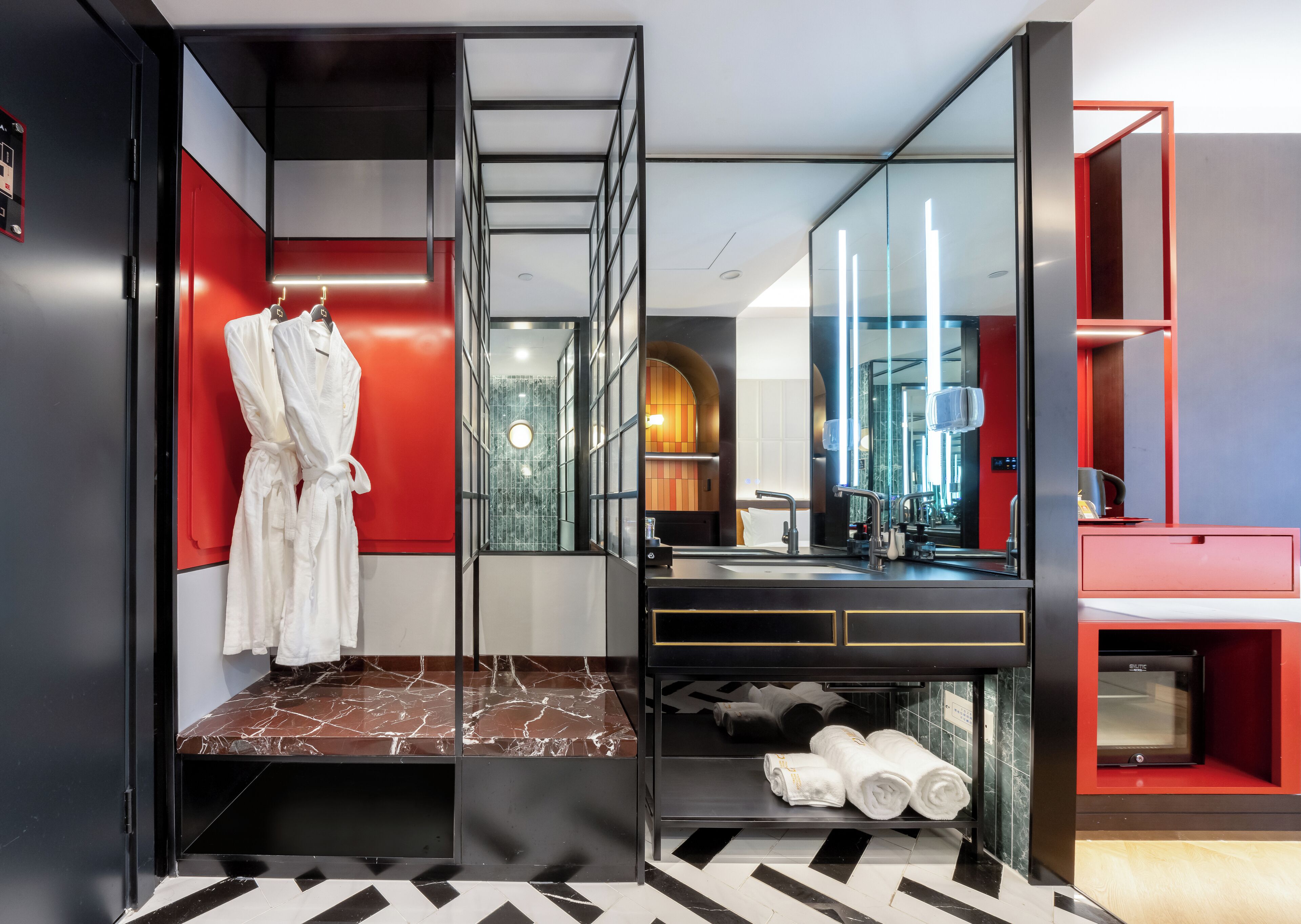 A modern bathroom with a large mirror, a robe rack, and a marble-tiled vanity.