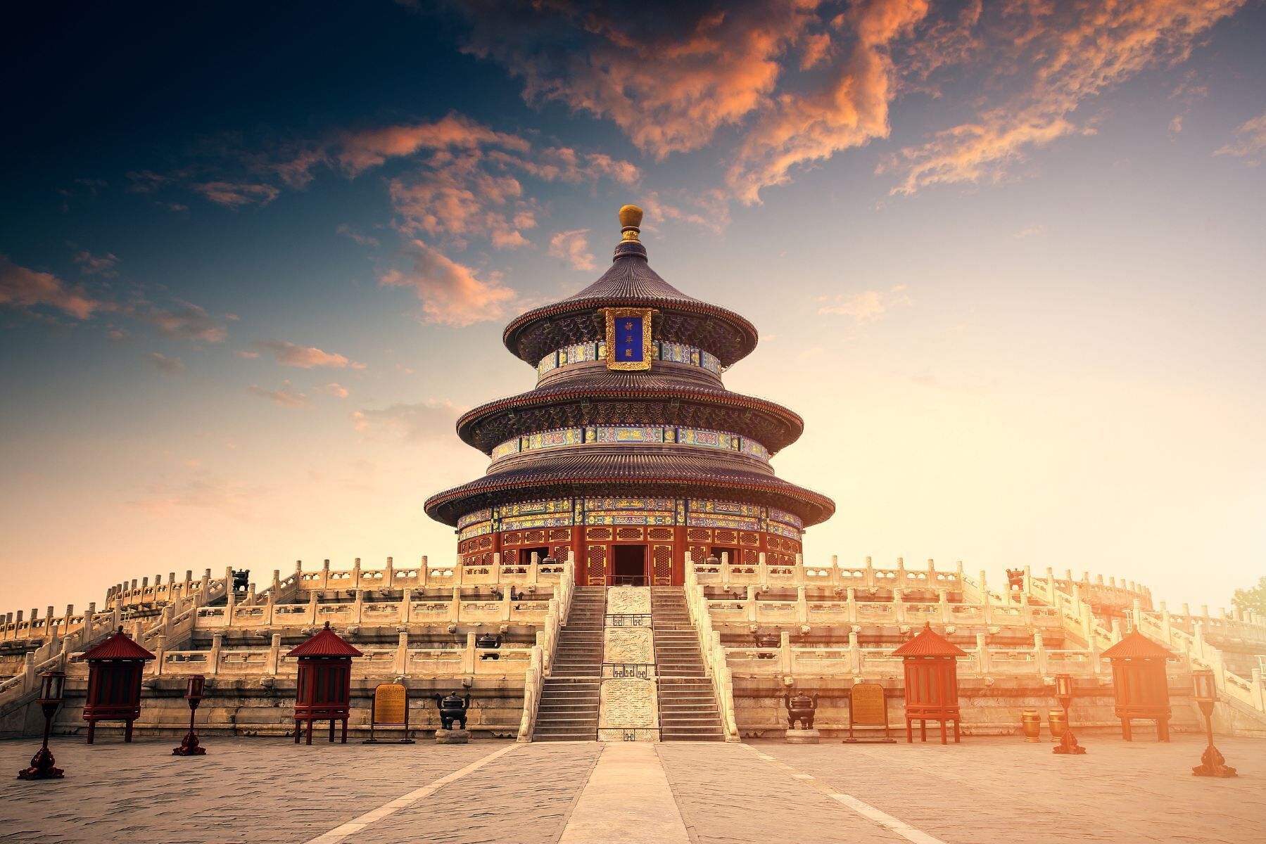 Une pagode chinoise traditionnelle, dotée d’un toit à plusieurs niveaux, entourée d’escaliers en pierre et d’un mur de pierre.