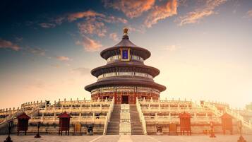A traditional Chinese pagoda with a multi-tiered roof, surrounded by stone steps and a stone wall.