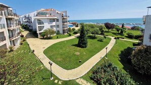 Un ensemble immobilier résidentiel comprenant plusieurs balcons, une pelouse bien entretenue et une vue dégagée sur la mer.