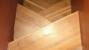 Eine Holztreppe mit Fischgrätmuster, die zu einem Raum mit Holzwänden und einer weißen Decke führt.