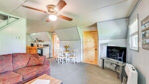 Ein kompakter Wohnbereich mit Sofa, Esstisch mit Stühlen, Fernseher und Deckenventilator.