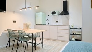 A compact kitchen with a dining area, a microwave, a sink, and a shelf with kitchen items. - 💫romantic Apartment by Virkin Suites 4💫a 7 Minutos Andando del Oceanográfico! (València)