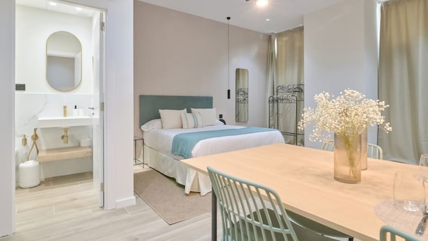 A modern hotel room with a bed, bedside table, and a dining area with a table and chairs. - 💫romantic Apartment by Virkin Suites 4💫a 7 Minutos Andando del Oceanográfico! (València)
