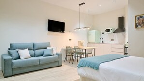 A modern bedroom with a sofa, a bed, a dining area, and a kitchenette. - 💫romantic Apartment by Virkin Suites 4💫a 7 Minutos Andando del Oceanográfico! (València)