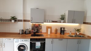 Moderni keittiö, jossa on sisäänrakennettu pesukone, uuni ja kahvinkeitin.