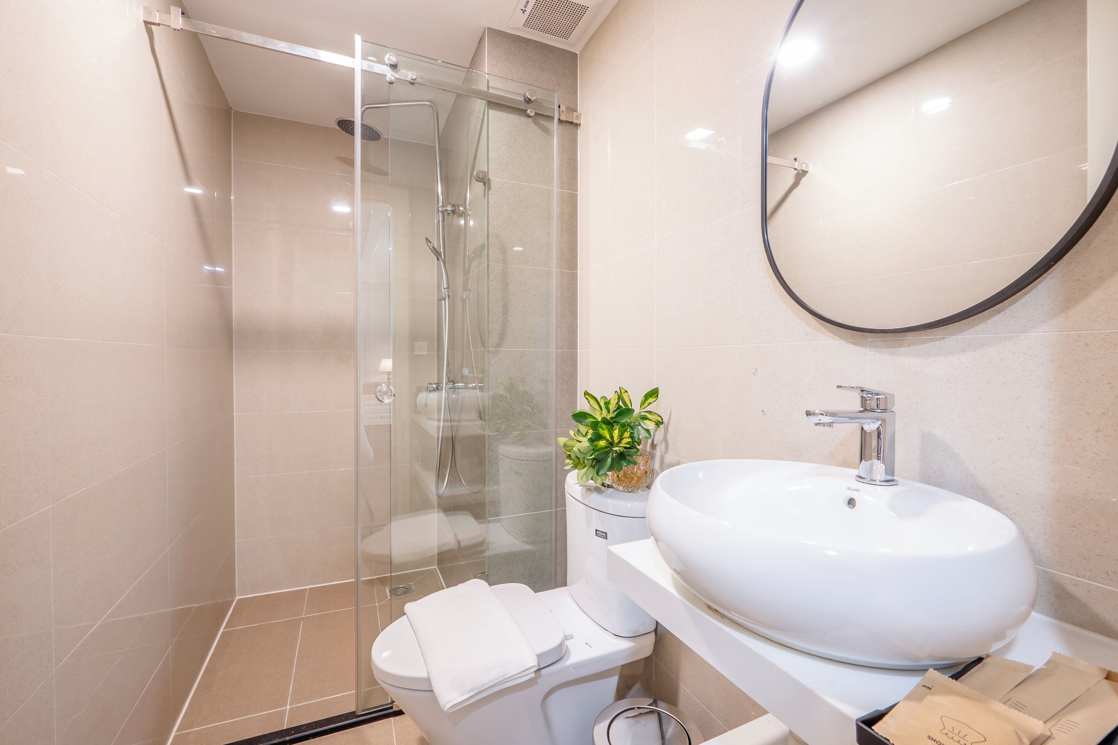 A modern bathroom with a glass-enclosed shower, a white sink, and a toilet.