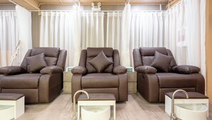 A spa room with three reclining massage chairs, a footrest, and a small sink. - Level Saigon hotel (Ho Chi Minh City)