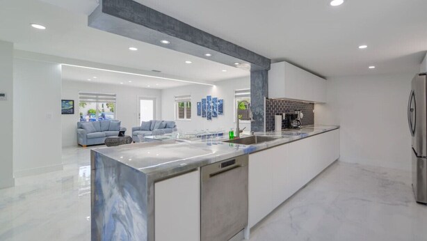 A modern kitchen with a marble countertop, stainless steel appliances, and a large island.