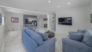 A modern living room with a sofa, a coffee table, and a flat-screen TV mounted on the wall.