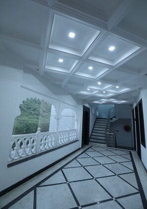 A hallway with a tiled floor, a staircase, and a decorative railing. - Arryaa Inn (Udaipur)