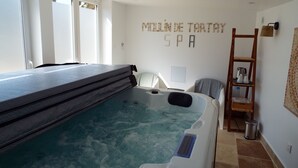 Um espaço de spa com hidromassagem, uma escada de madeira e um armário com artigos de higiene pessoal.