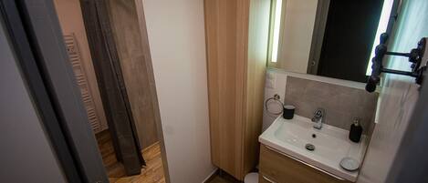 A compact bathroom with a wooden vanity, a mirror, and a toilet.