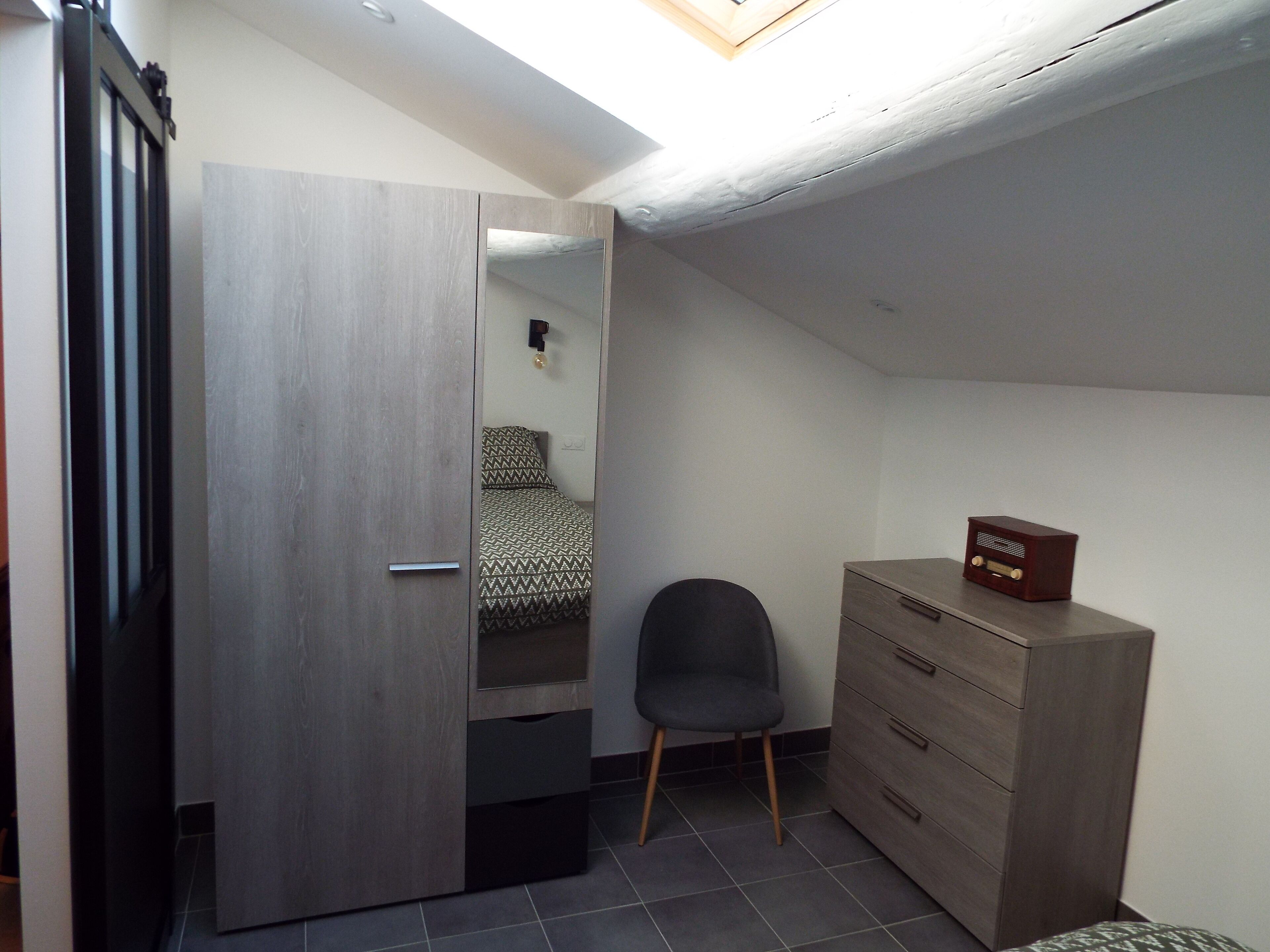 Ein Schlafzimmer mit einem Bett, einem Schminktisch, einem Sessel und einem Kleiderschrank.