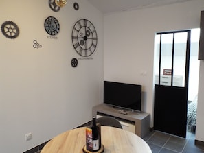 Une chambre moderne équipée d’un téléviseur à écran plat, d’une table à manger en bois et d’horloges murales portant les inscriptions « SYDNEY » et « JOHANNESBURG ».